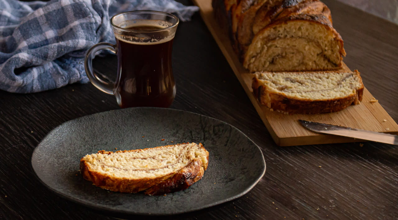 fatia de babka de canela servida num prato e uma xícara de café