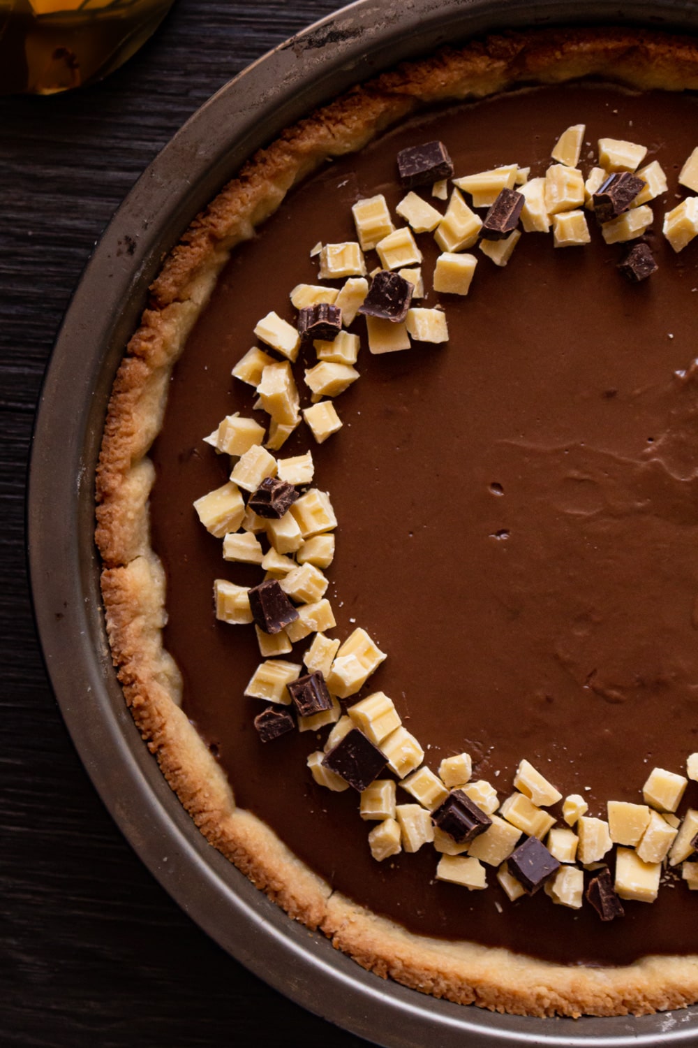 foto de cima de uma torta de chocolate com pedacinhos de chocolate branco por cima