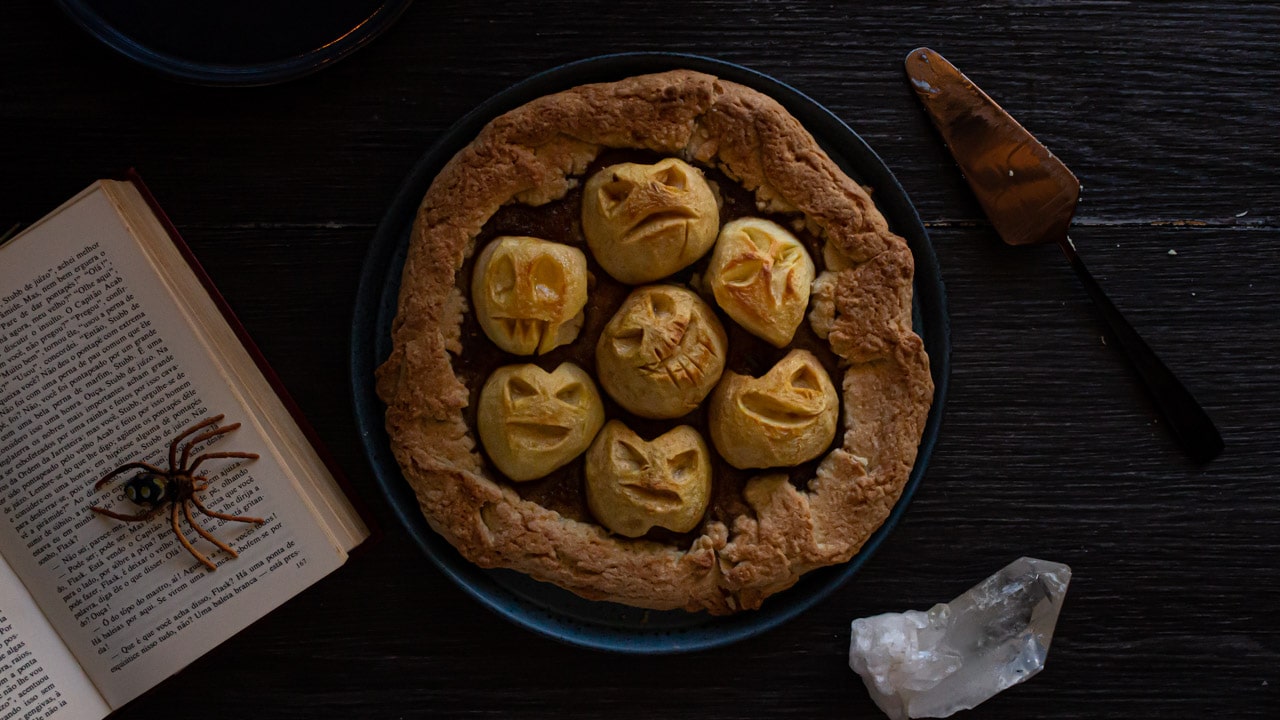 foto de cima da versão de dia das bruxas da torta rústica de maçã com as maçãs esculpidas com carinhas