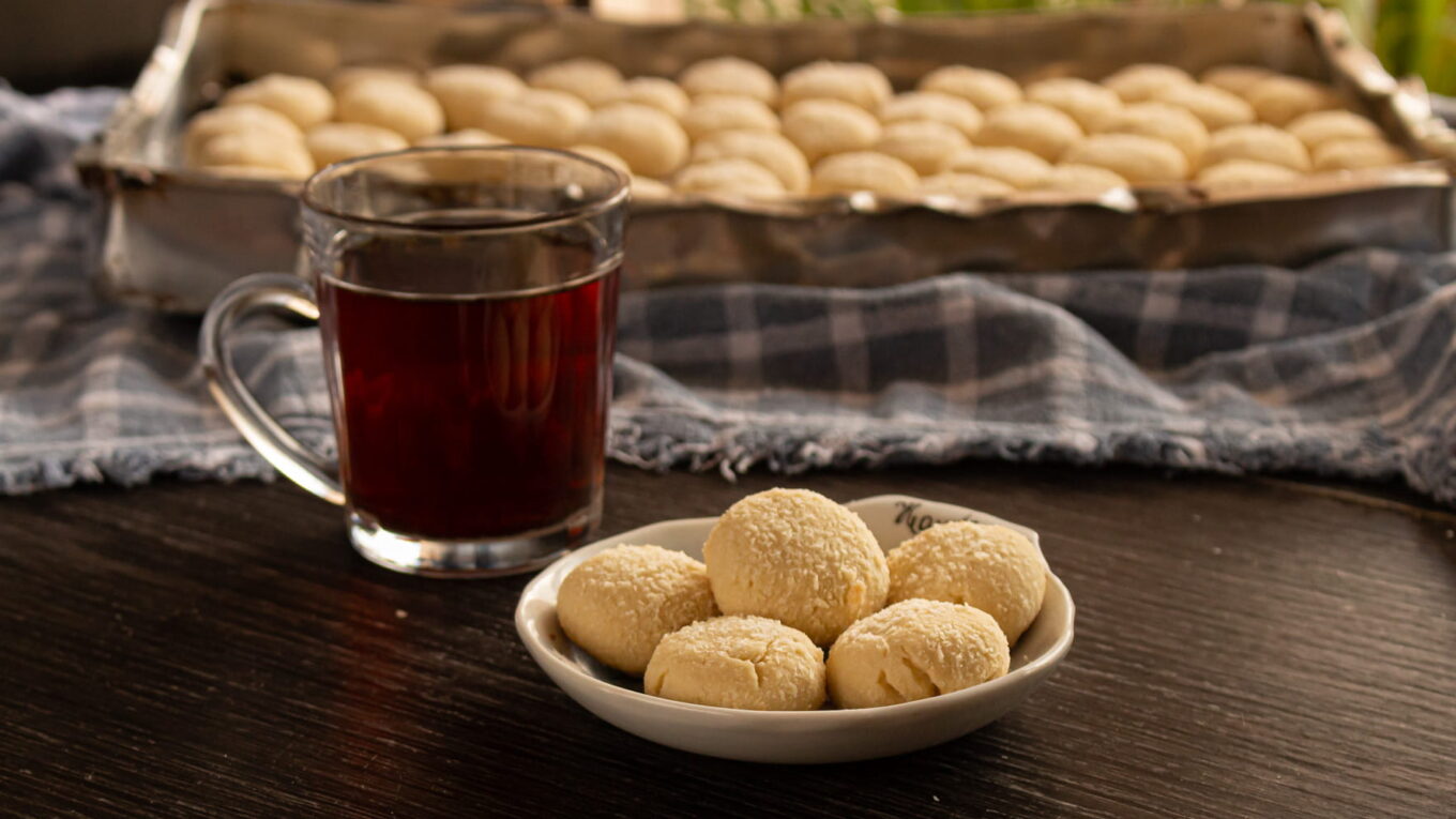 foto de um pratinho com biscoitos amanteigados de coco e uma xícara de chá do lado