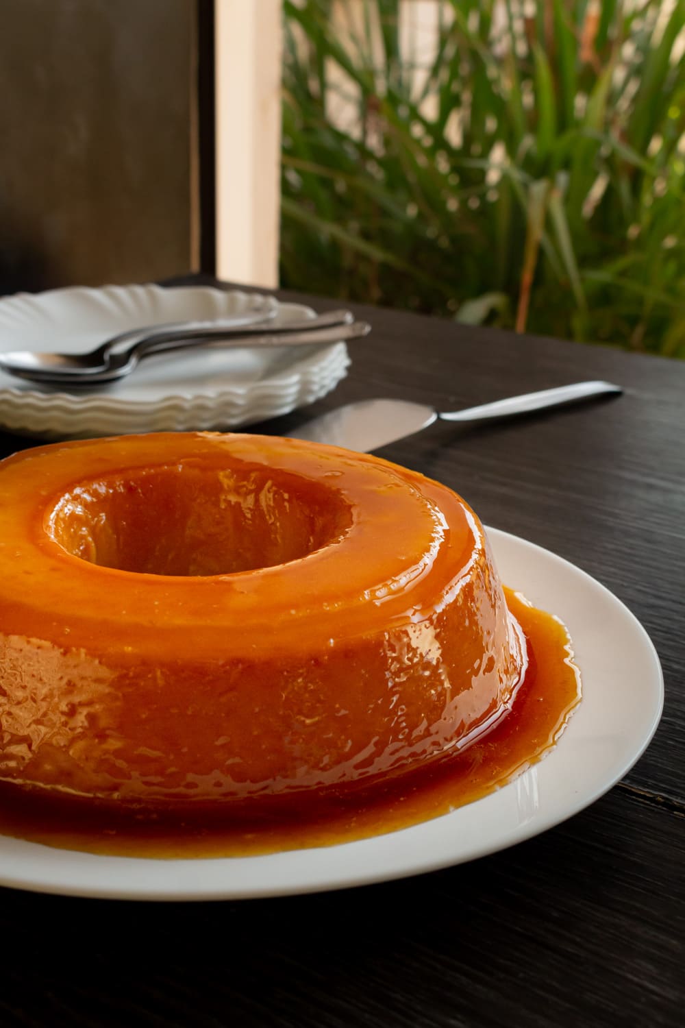 visão de frente de um pudim de padaria sobre um prato branco 