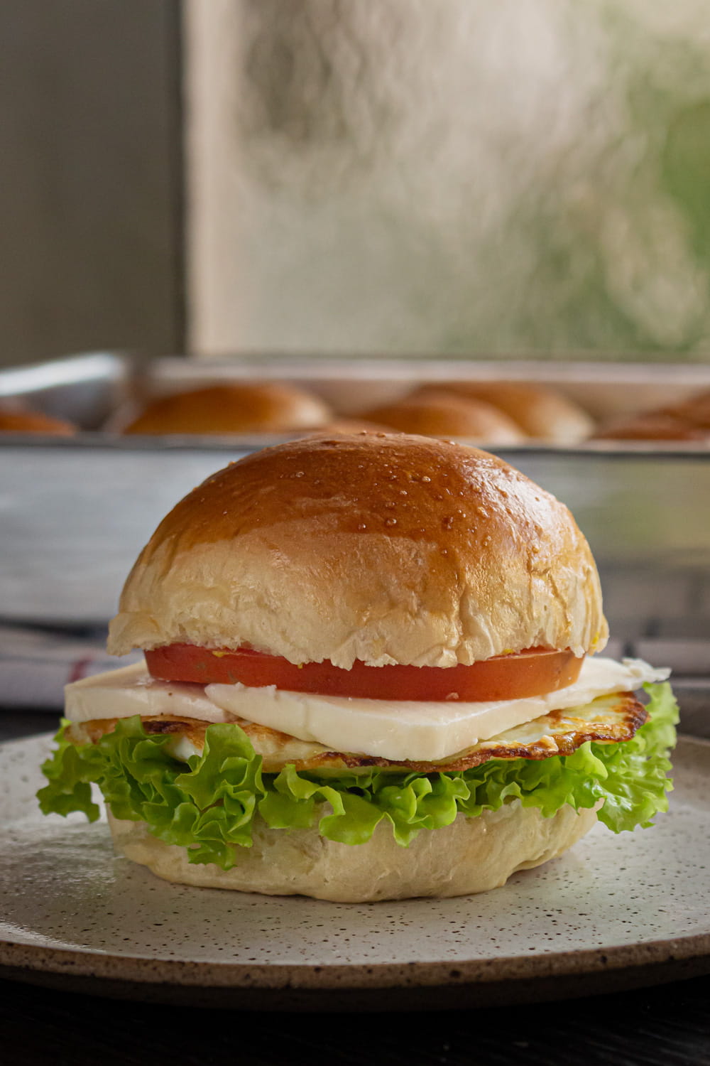 sanduíche de pão de batata com alface, ovo frito, queijo e tomate