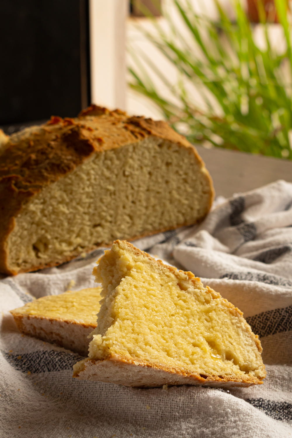 fatia de soda bread com manteiga e o pão partido lá no fundo da foto