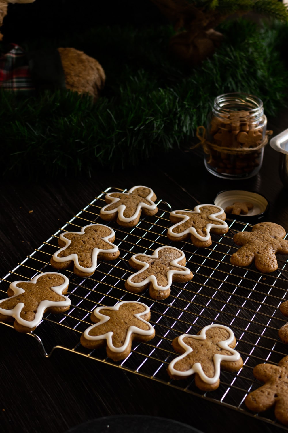 foto de biscoitos de gengibre em formato de boneco sobre uma grade de metal. A maioria dos biscoitos está contornado com glacê branco