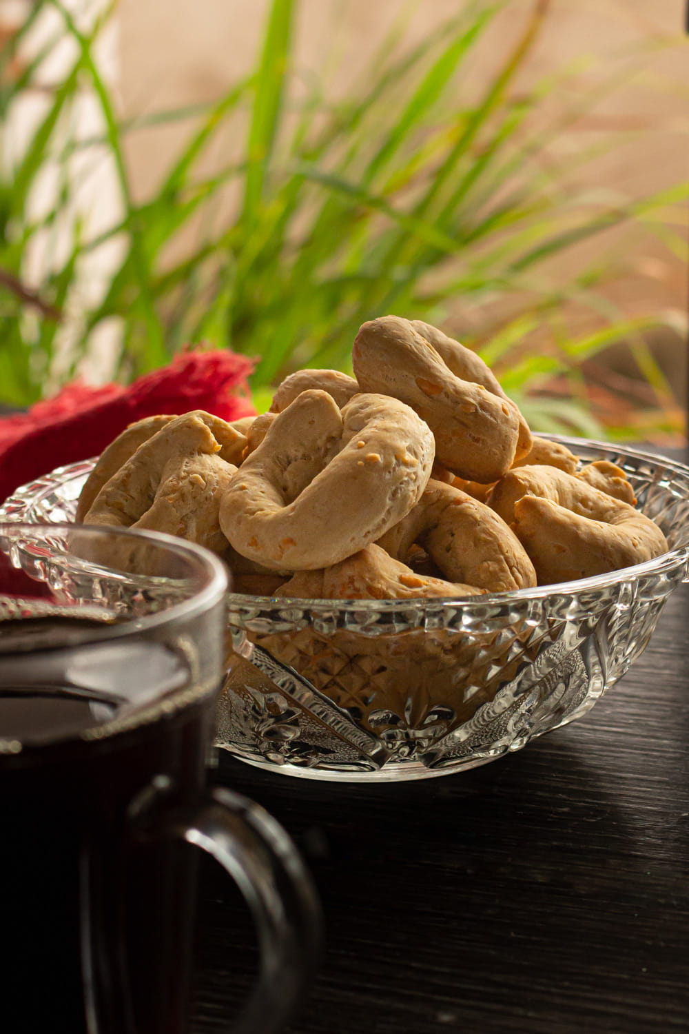 tigela de vidro cheia de biscoitinhos de queijo e sal amoníaco, ao lado de uma xícara de café