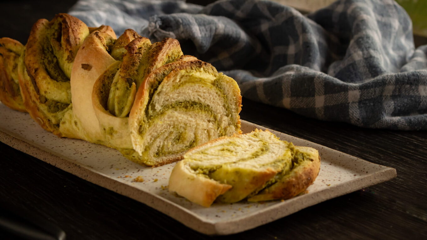 Pão trançado com pesto, cortado mostrando a espiral verde no miolo
