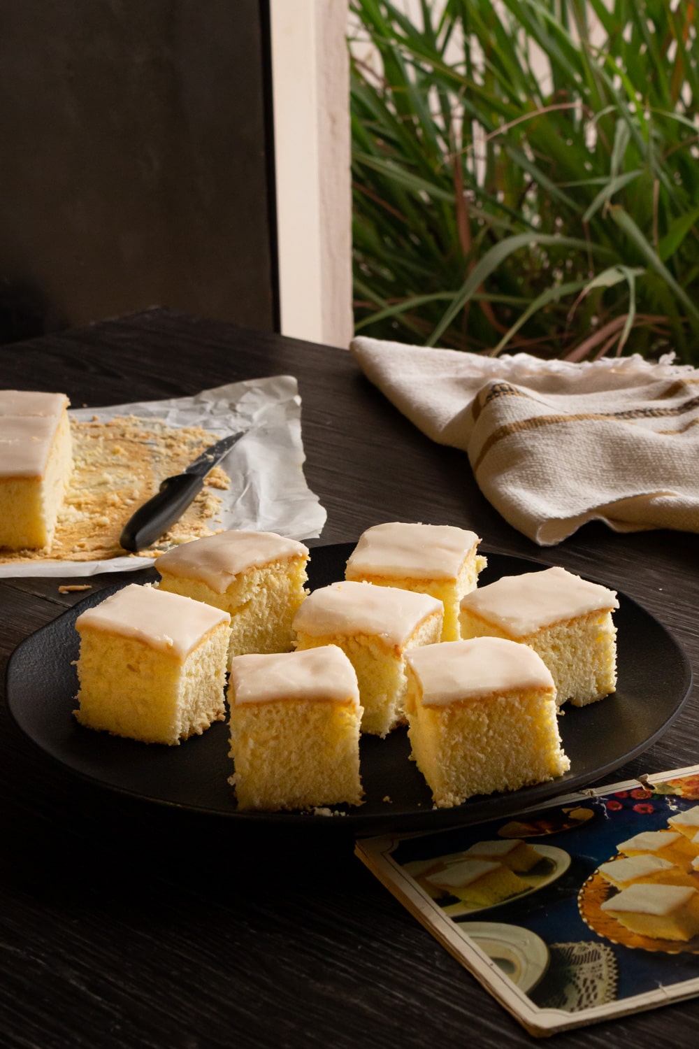 prato de pedaços quadrados de bolo branco com uma cobertura branca no topo