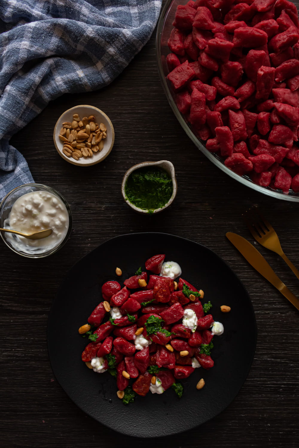 foto aérea mostrando o prato com nhoque de beterraba, um potinho com molho pesto, outro com cottage e outro com amendoins
